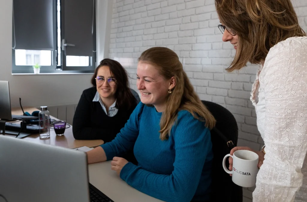 Three women collaborating at a computer in office.