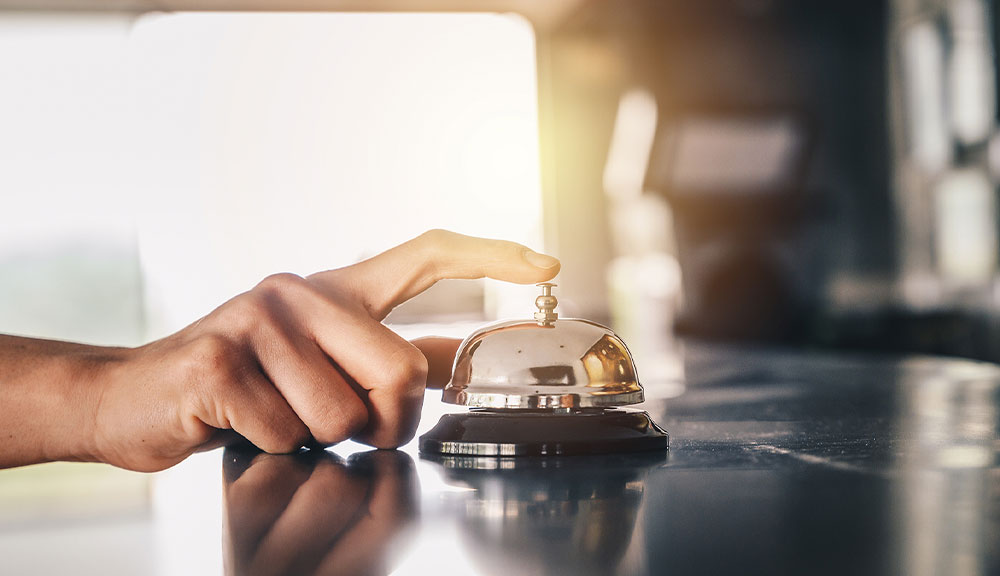 Person pressing a service bell on counter