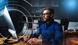 Man working on computer with digital graphics overlay.