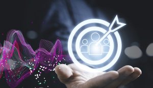 Hand holding digital target with people icons.