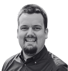 Smiling person in a collared shirt, black and white.