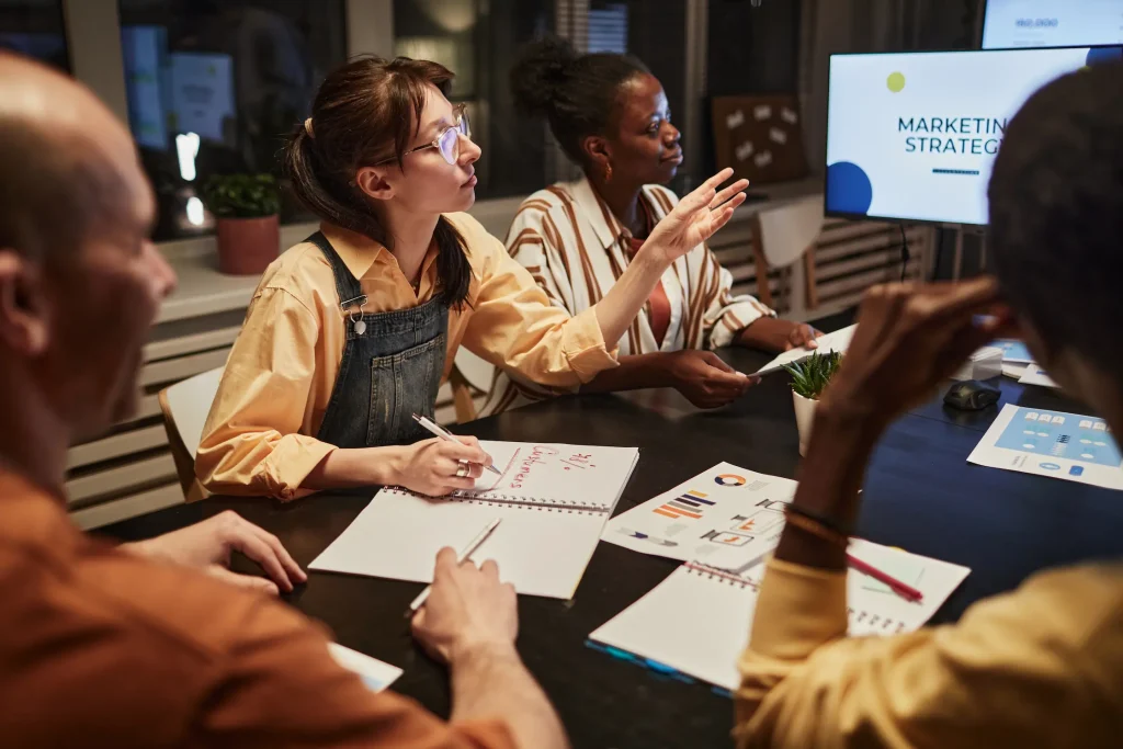 Equipo discutiendo la estrategia de marketing en una mesa de reuniones.