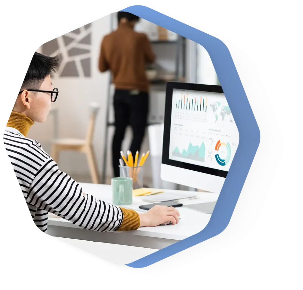 Person analyzing data on computer screen in office.