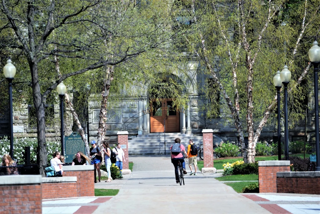 Étudiants devant un bâtiment universitaire arboré