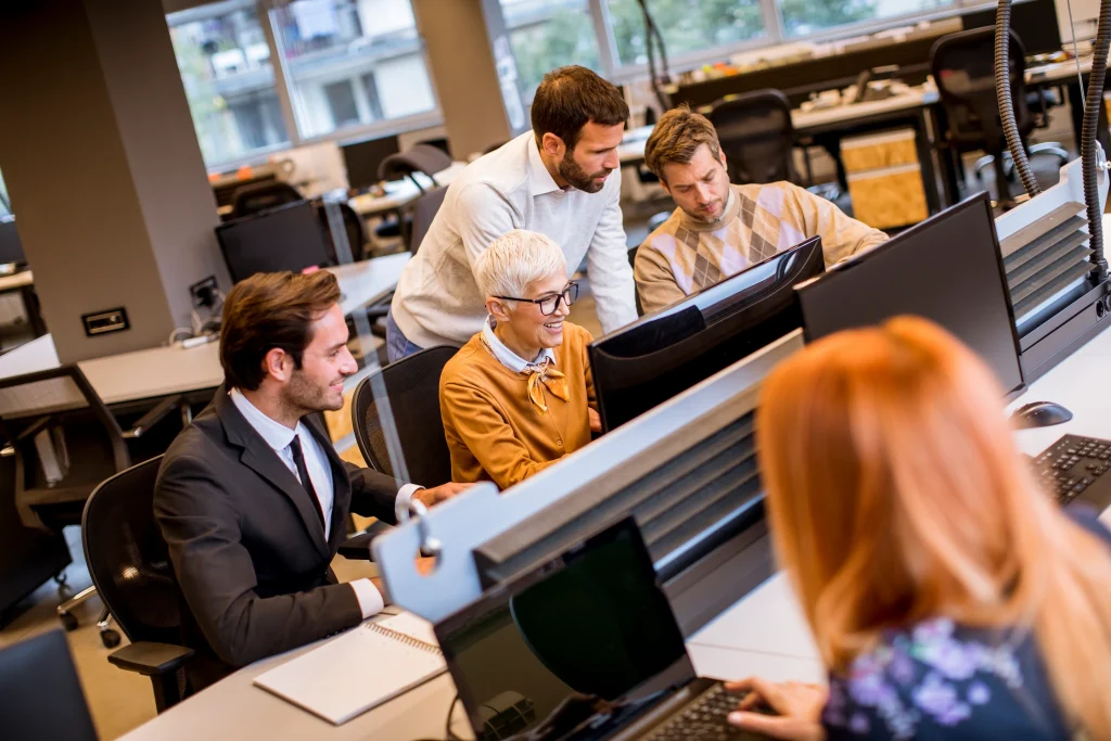Collègues collaborant devant ordinateurs dans open space